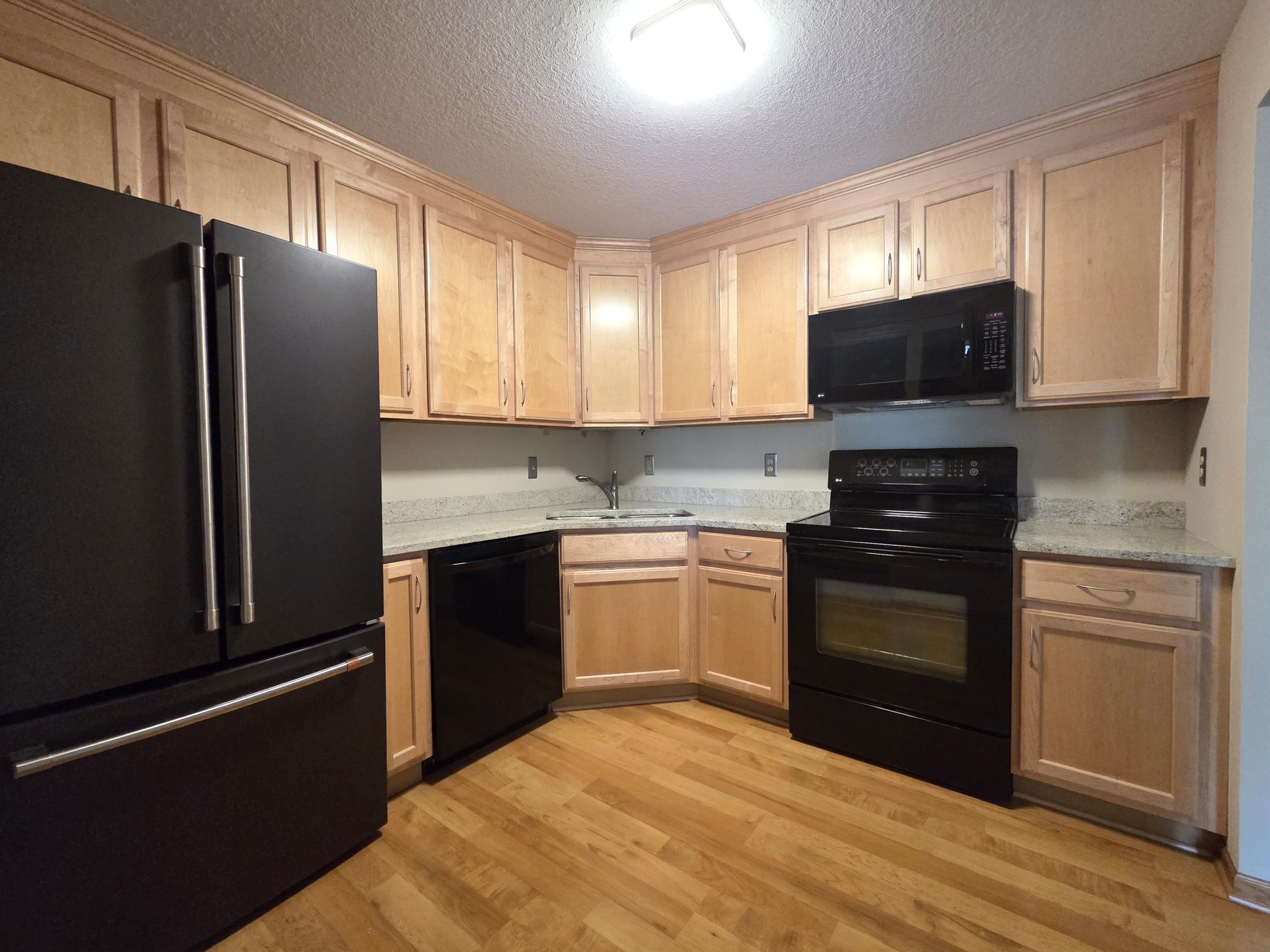 Kitchen with newer maple cabinets, grantie counter-tops, laminate flooring, and appliances in 2009, but newer fridge new in 2022.