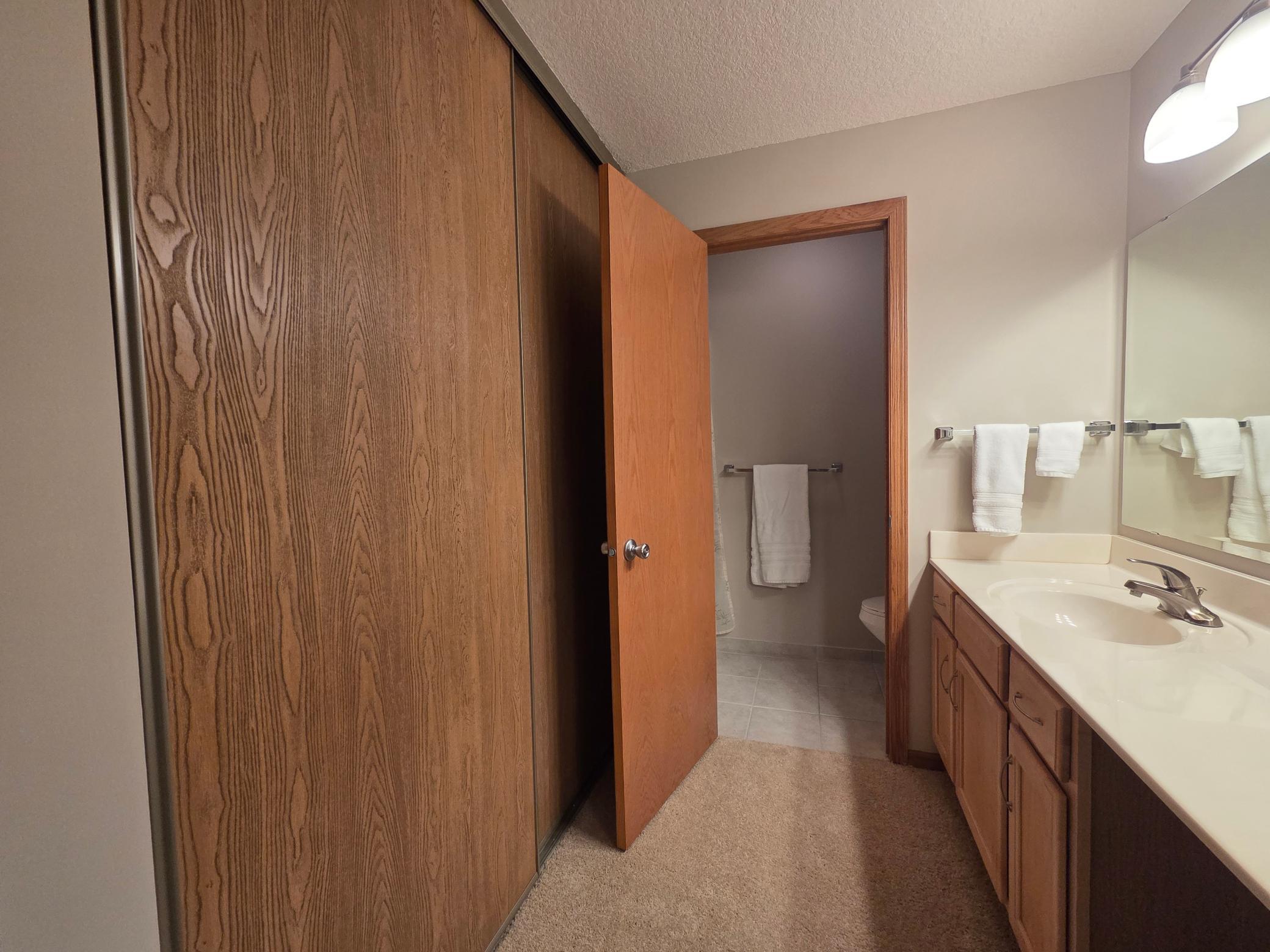 Primary bath with large closet, large vanity with make-up area, and a door dividing the shower & toilet with ceramic flooring.