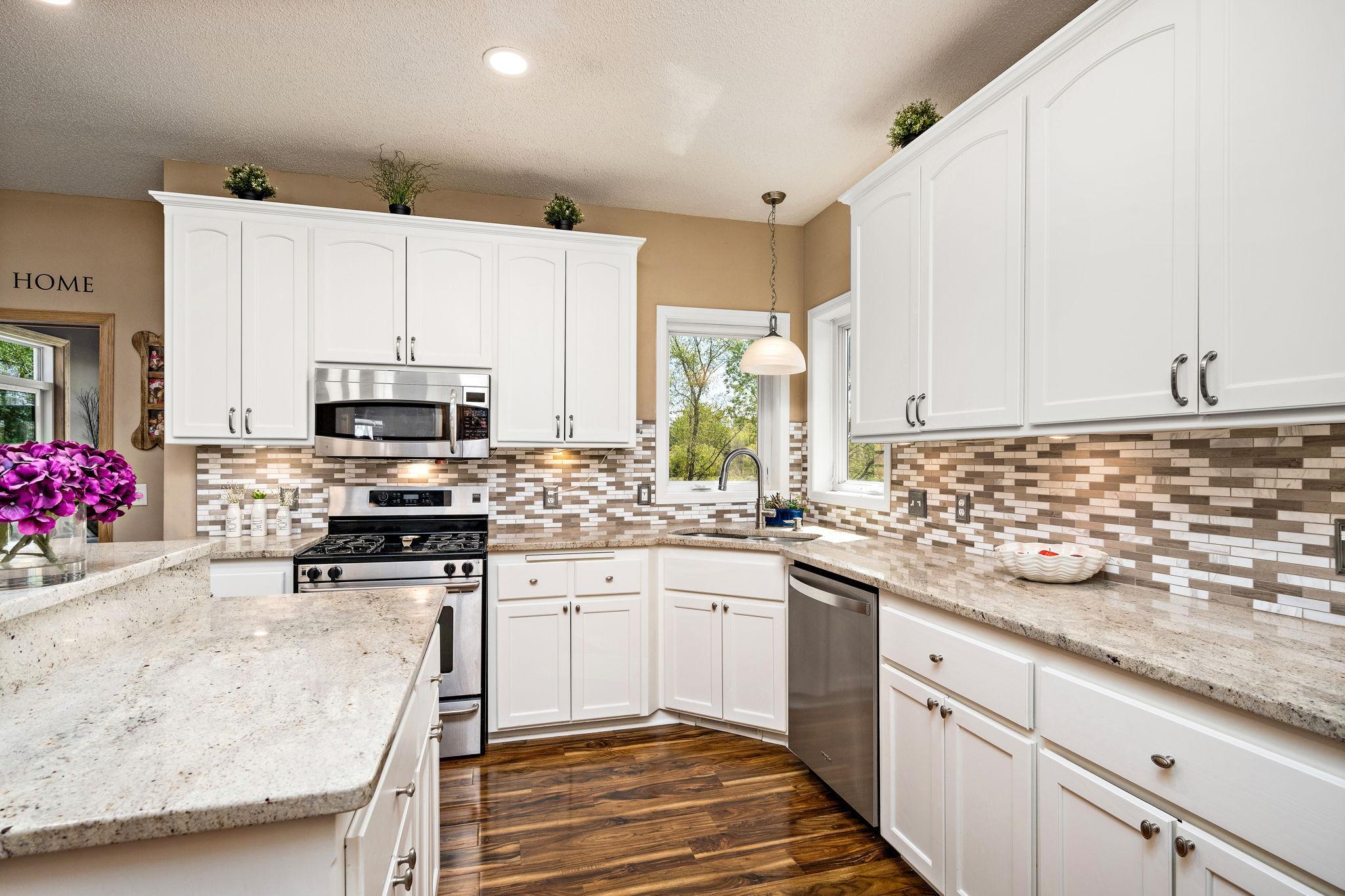 Kitchen has granite counter tops and corner window