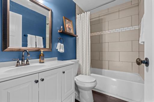 Full bathroom on the main features tiled shower, ceramic tiled floors, and a fun pop of color.