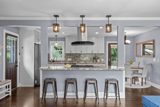 The kitchen showcases granite countertops, an oversized breakfast bar that creates a seamless open flow, stainless steel appliances, a gas cooktop, and a stylish tiled backsplash.
