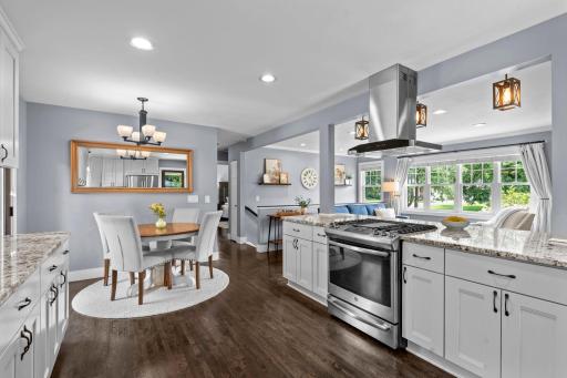 The kitchen showcases granite countertops, an oversized breakfast bar, stainless steel appliances, a gas cooktop, beautiful hardwood floors. Seamless open main level with large windows that fill this space with an abundance of natural light.