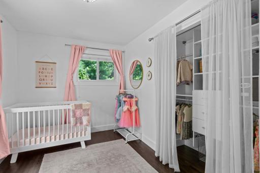Additional spacious, main-level bedroom features double windows, gorgeous floors and neutral, white color palette, and closet organization system.