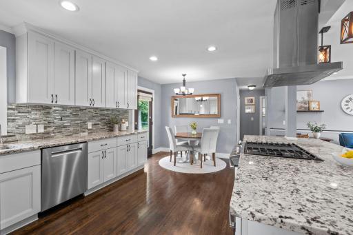 Thoughtfully remodeled with quality craftsmanship and attention to detail, the kitchen showcases granite countertops, an oversized breakfast bar, stainless steel appliances, a gas cooktop, and a stylish tiled backsplash.