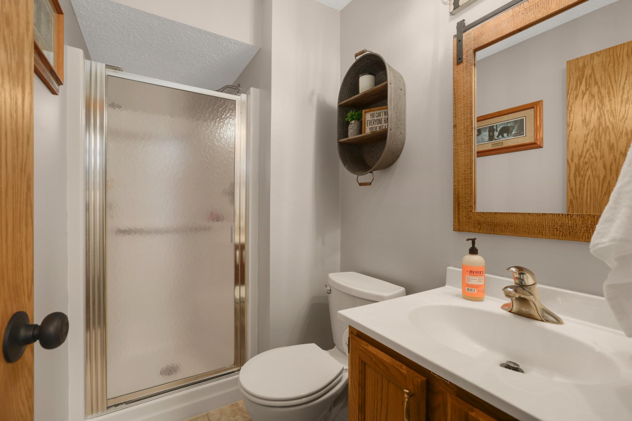 This lower-level bathroom is clean, functional, and thoughtfully updated with a warm, neutral design. Featuring a walk-in shower with frosted glass doors, updated fixtures, and easy-care finishes, the space offers both comfort and convenience.