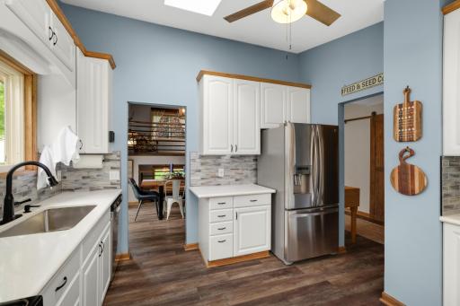 The contemporary tile backsplash & updated black hardware provide a stylish finishing touch throughout the kitchen. The kitchen also features durable updated flooring, a skylight, ceiling fan, & ample cabinetry for storage & organization.