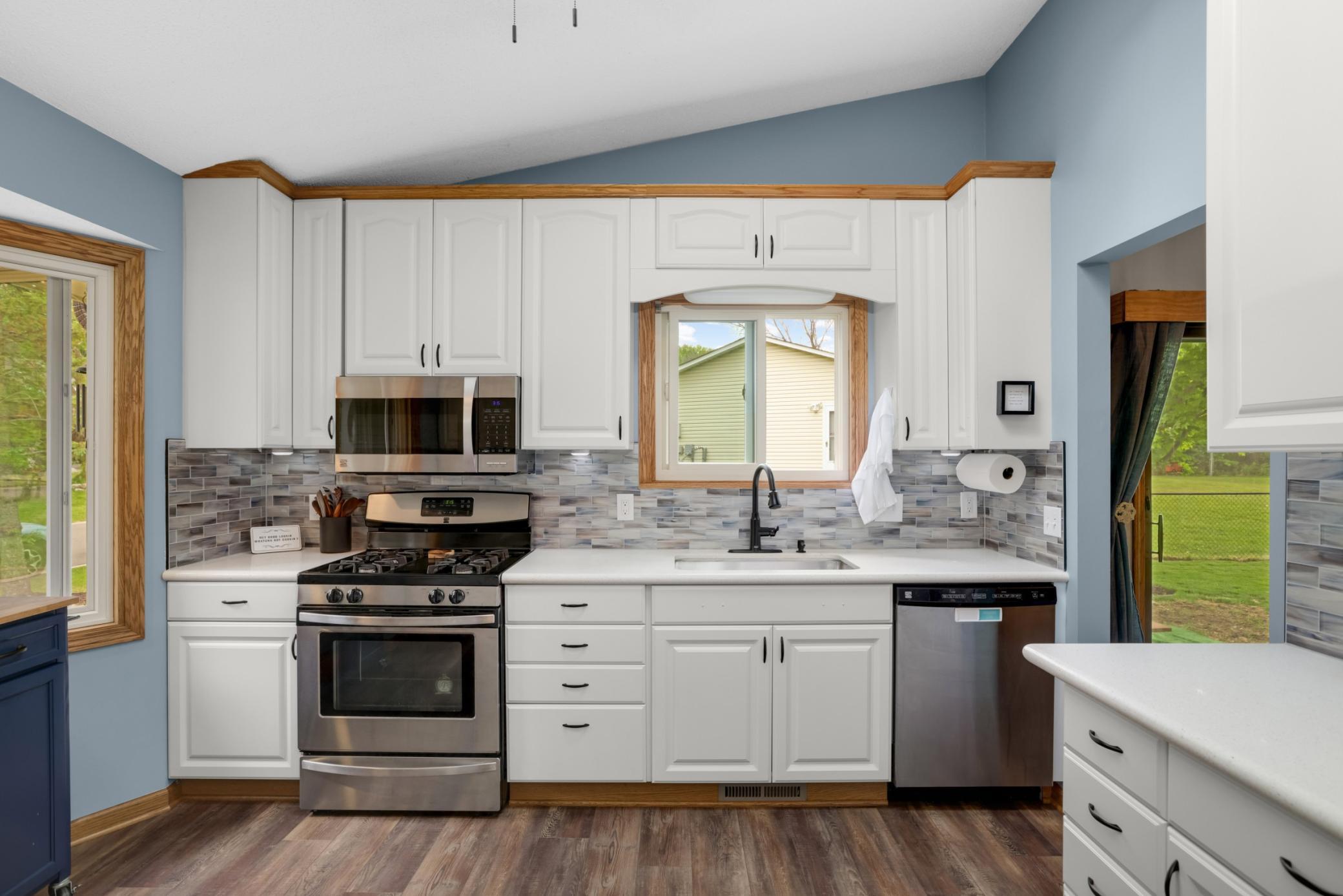 This beautifully updated kitchen combines timeless style with modern functionality. Crisp white cabinetry, sleek stainless steel appliances, & quartz-style countertops create a clean and inviting space, while the soft blue walls add warmth