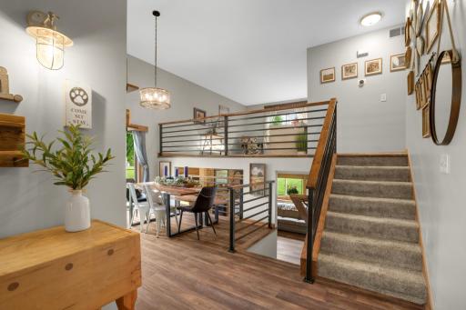 These stunning interior spaces showcase a bright and airy multi-level design filled with warmth and character. The open-concept layout features soaring vaulted ceilings, modern horizontal railing details, and rich wood accents