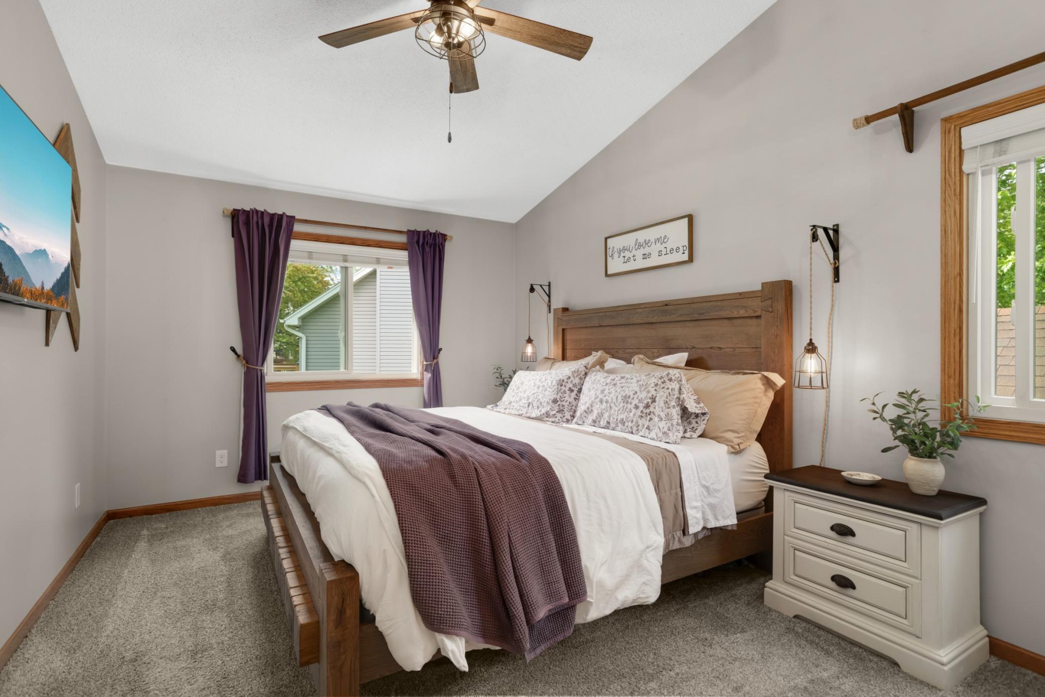 The spacious primary bedroom offers a peaceful retreat with soaring vaulted ceilings, soft neutral tones, & abundant natural light. The room easily accommodates a king-sized bed and features stylish updated lighting, & gives you the feeling of space