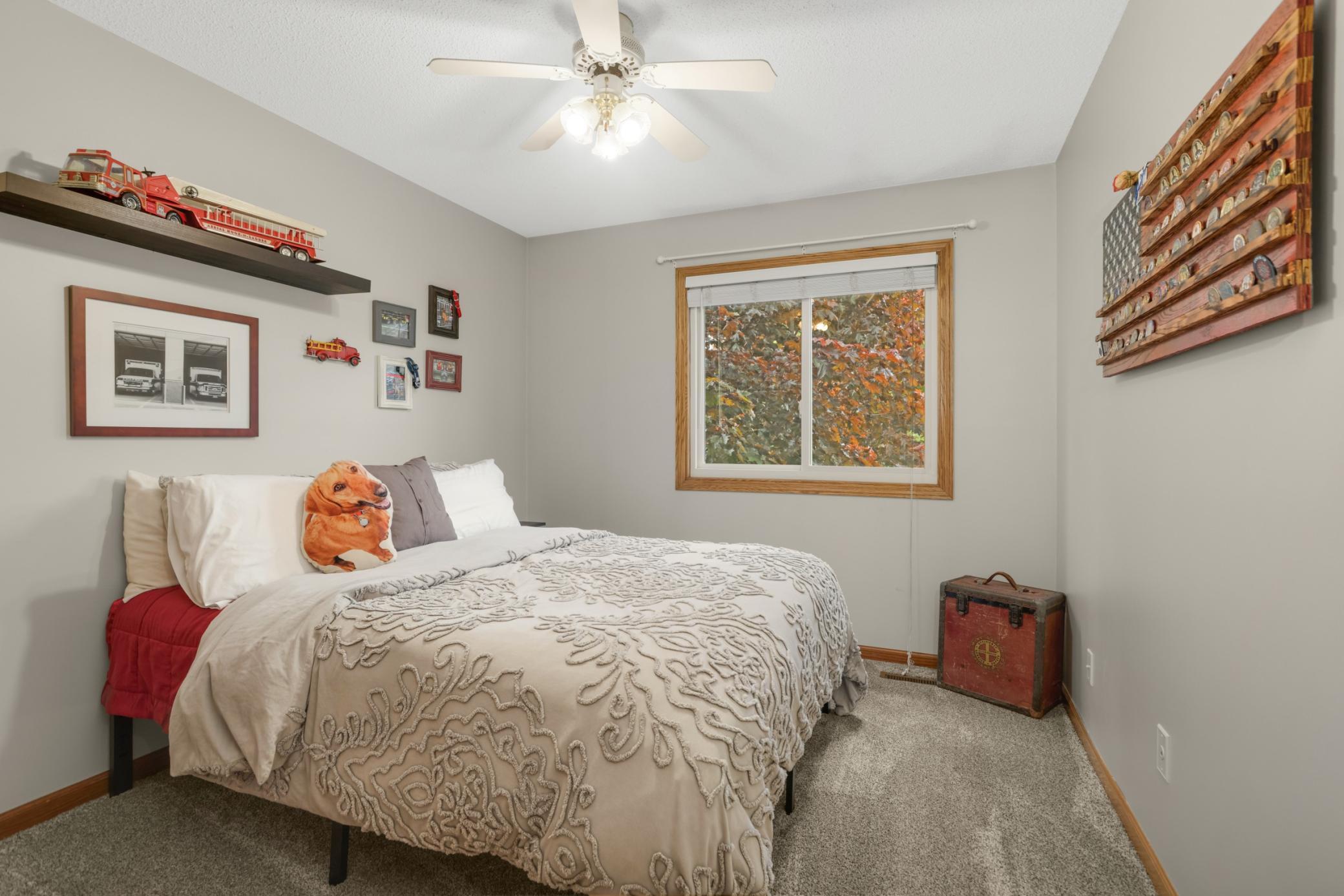 This comfortable 2nd bedroom offers a warm and inviting feel with neutral paint tones, plush carpeting, & abundant natural light. The large window frames beautiful tree views while filling the room with sunlight, creating a bright and cozy atmosphere
