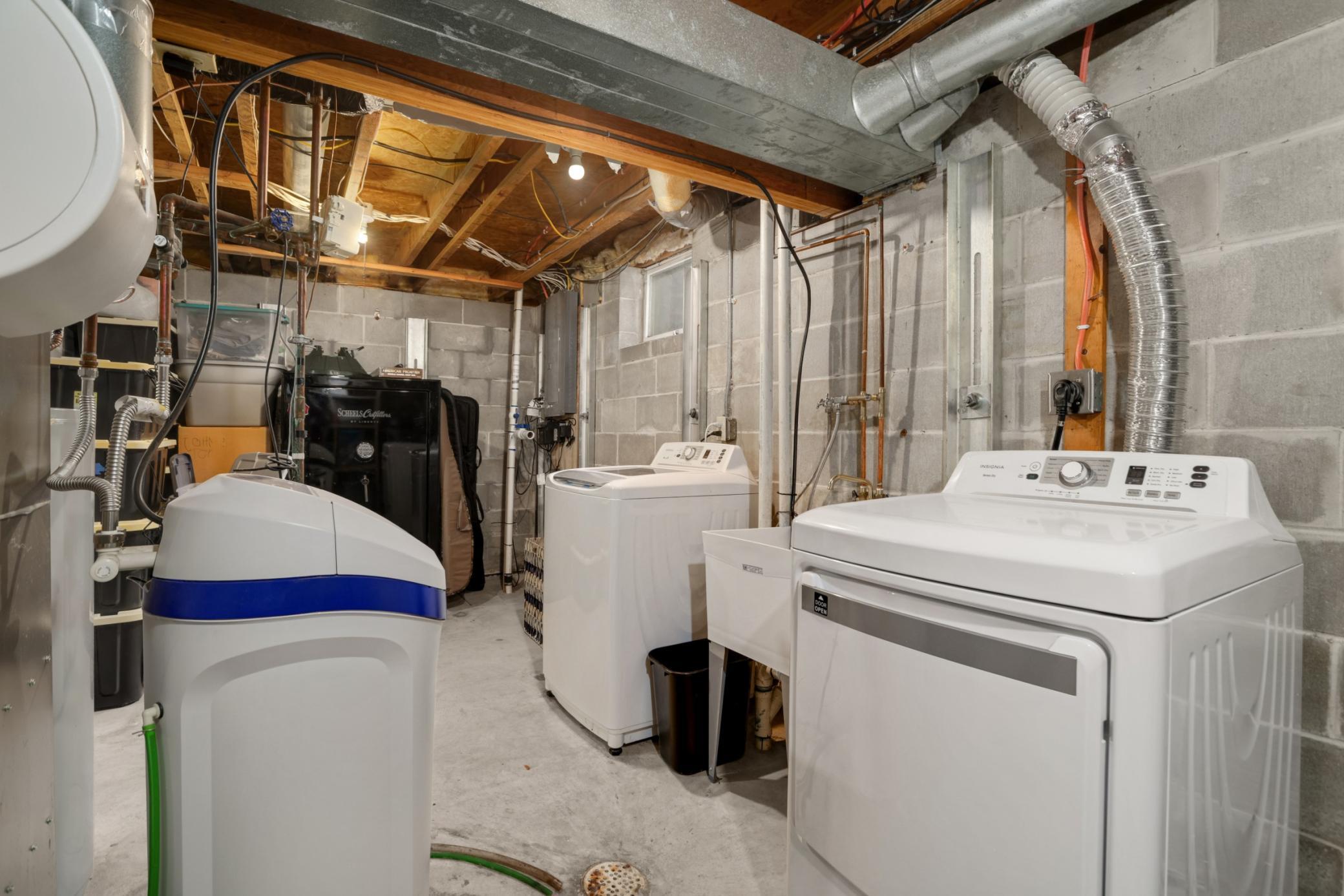 The laundry area is clean and practical, featuring a full-size washer and dryer new in 2021, utility sink access, and additional room for organization and storage and a new water softener in 2024.