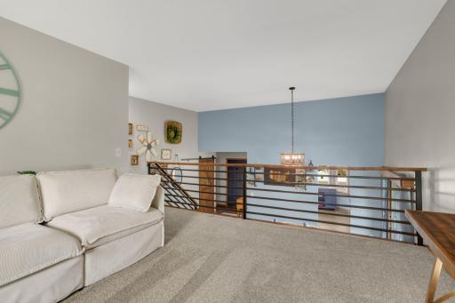 The versatile loft area is ideal for a second family room, reading nook, home office, or play space. Modern railing details and the open overlook add architectural interest and connect the space seamlessly to the rest of the home.