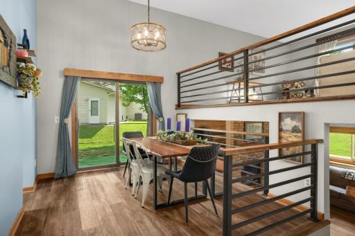 Natural light pours in through large windows and sliding glass doors, highlighting the updated flooring and spacious flow between living, kitchen and dining areas.