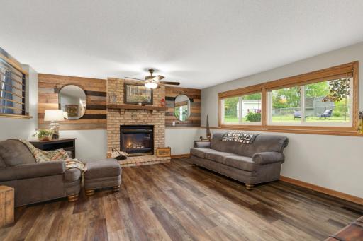 This spacious lower-level family room offers the perfect combination of warmth, comfort, and rustic charm. Centered around a cozy brick gas fireplace with a wood mantel and striking wood accent wall, the space creates an inviting atmosphere