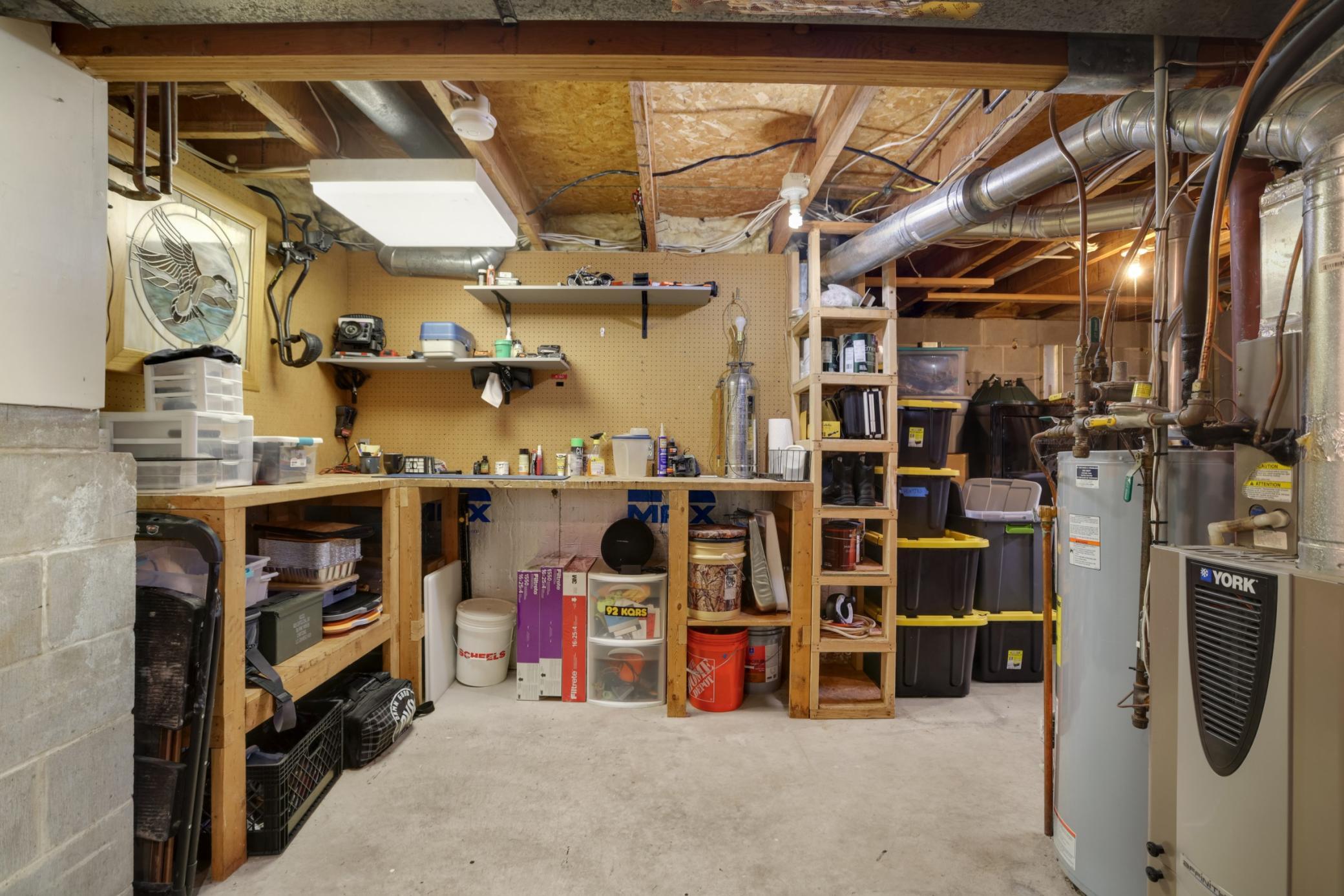 The spacious unfinished lower level features a dedicated workshop area complete with built-in workbenches, shelving, and abundant storage space—perfect for hobbies, tools, seasonal items, or home projects.