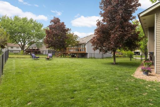 The backyard offers an exceptional outdoor setting with a large, fully fenced yard surrounded by mature trees and beautiful landscaping. The expansive green space provides plenty of room for entertaining, pets, play, or simply relaxing outdoors