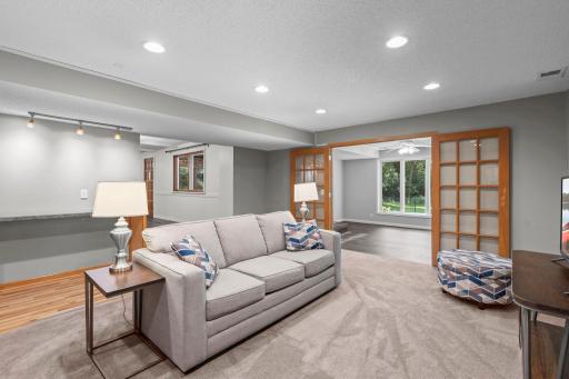 Lower-level family room with electric fireplace opens to a bright sunroom, providing flexible space for entertaining, hobbies, a reading nook, or quite relaxation.