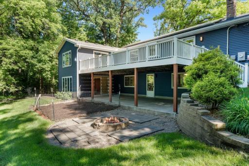 Back yard features large patio under deck with a fire pit and fenced garden area.