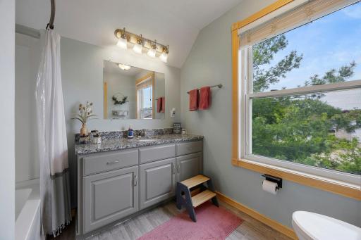 Full bath has granite counters, cabinet space and views of the trees