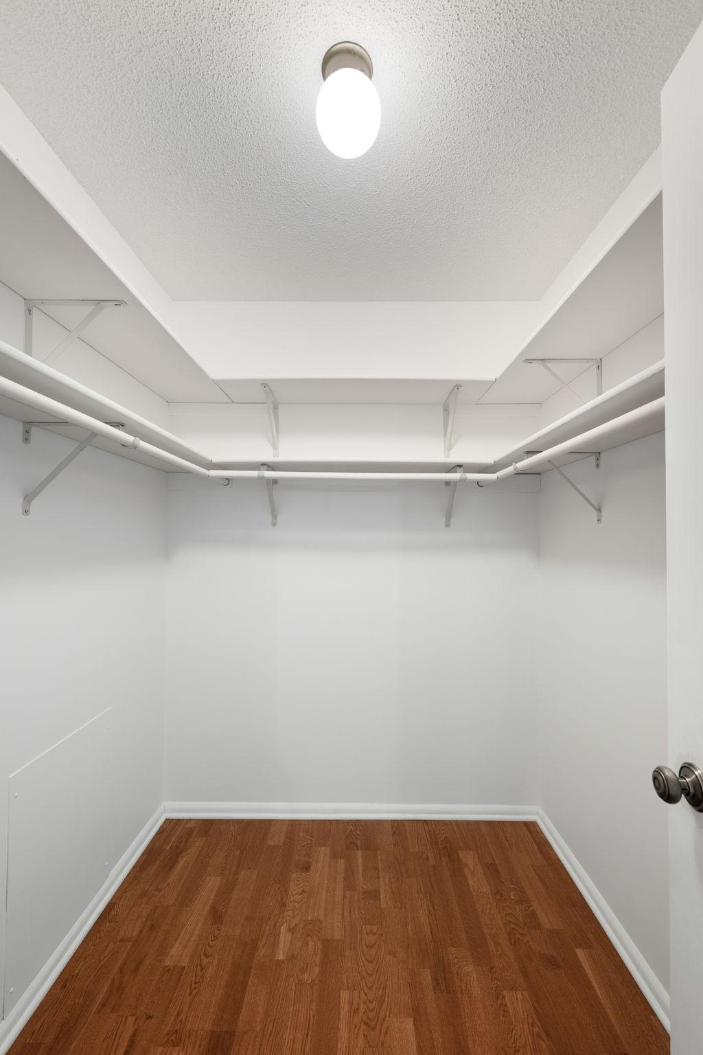 Walk-in closet with built-in shelving and hanging space for added storage.