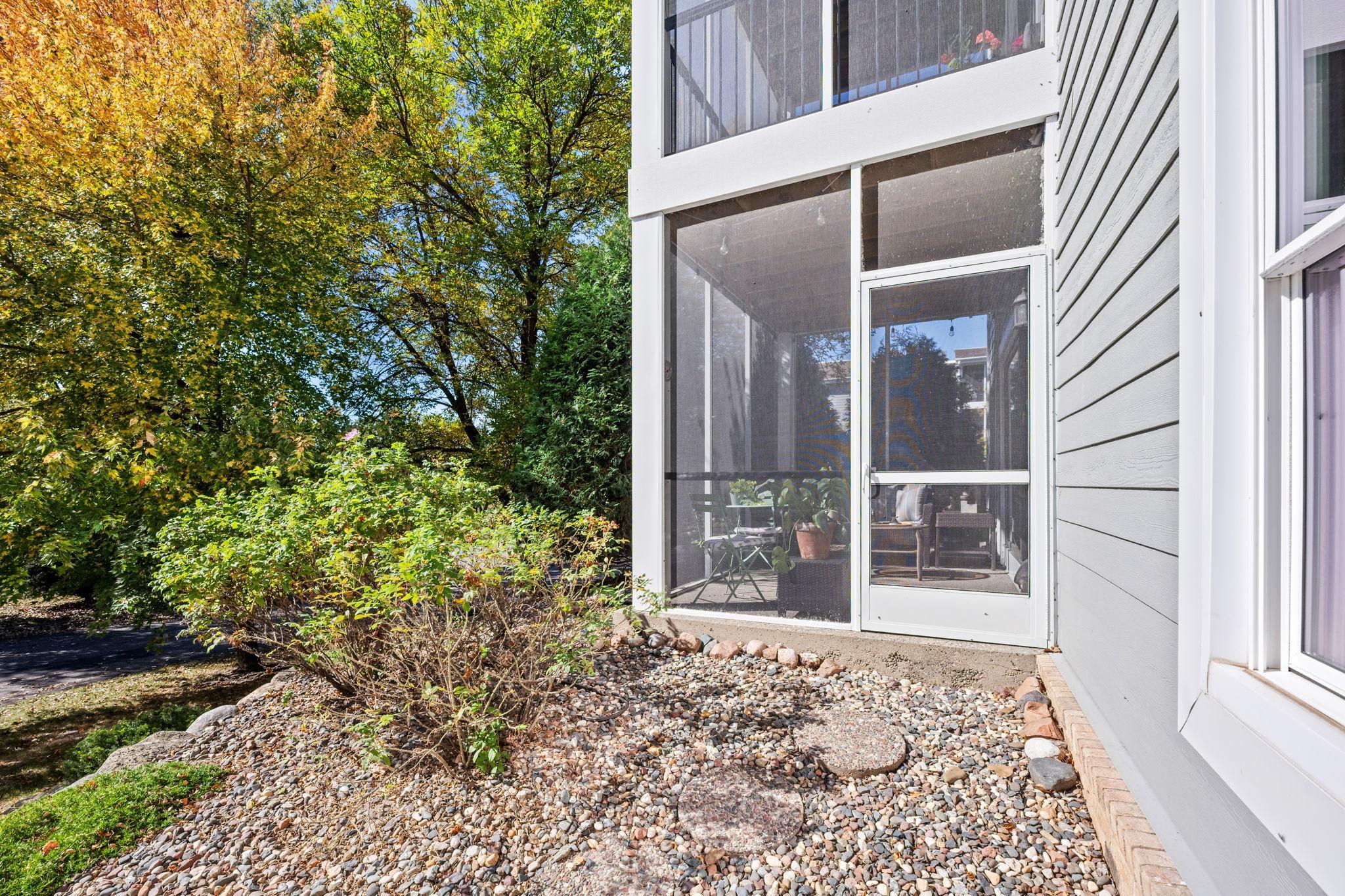 Exterior view of the screened porch and landscaped surroundings.