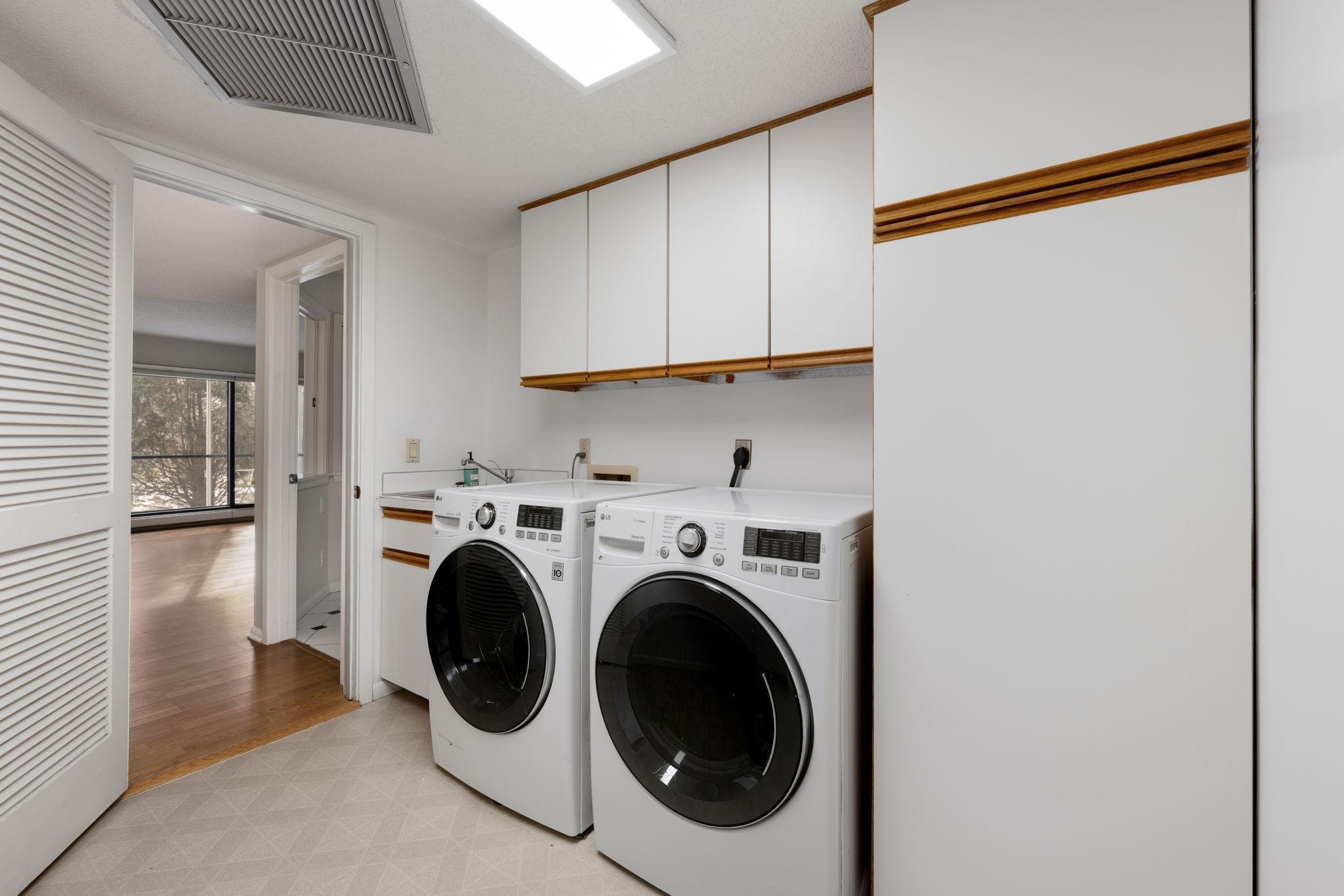 Updated In-unit laundry area with cabinetry and side-by-side washer and dryer.