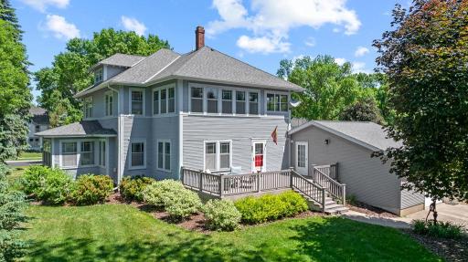 Rear view of the home shows a spacious back deck ready to enjoy your partially private backyard surrounded by mature trees and greenery