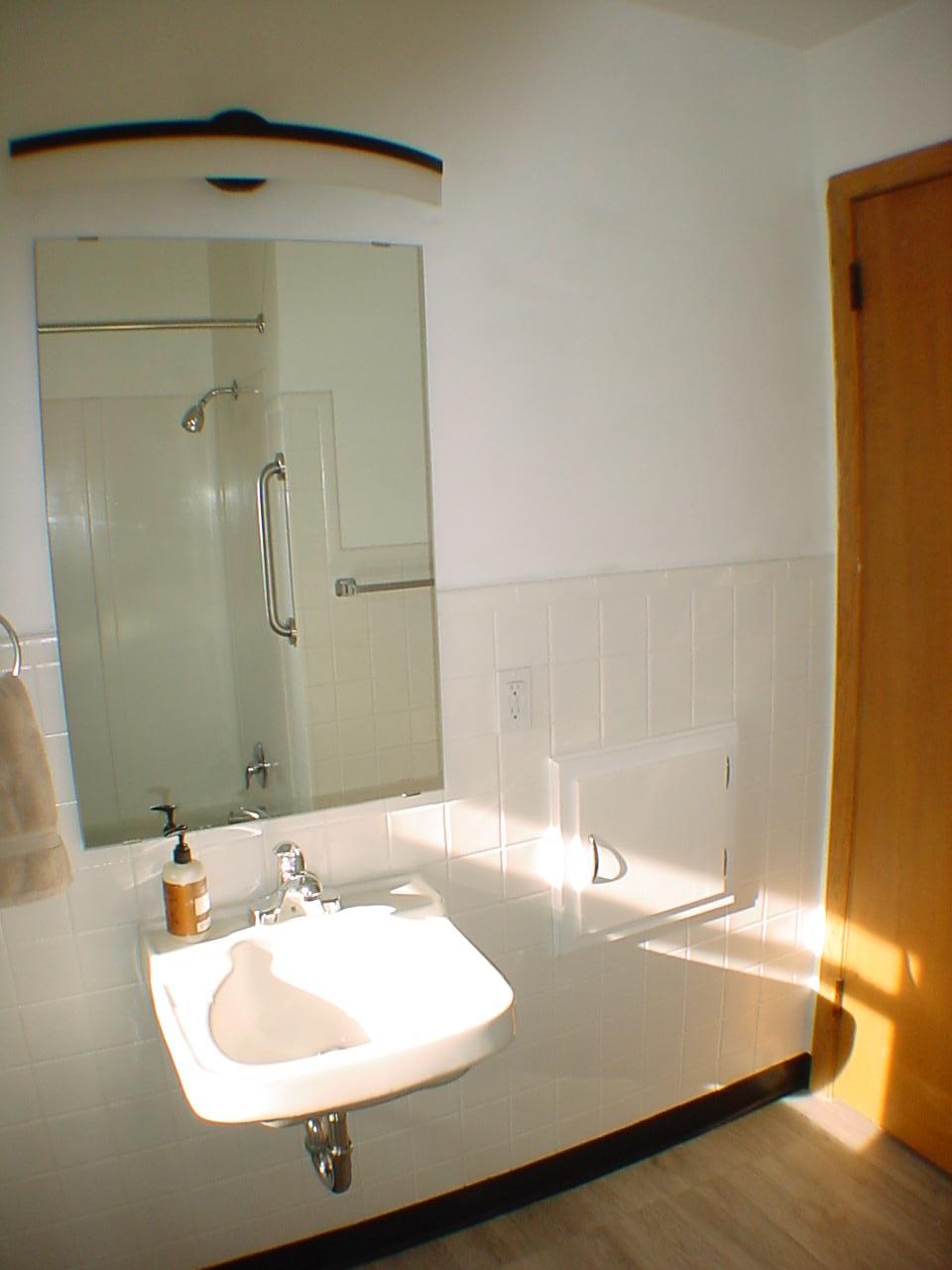 Retro main level full bath hosts laundry shoot with neutral decor. Add your personal touch.