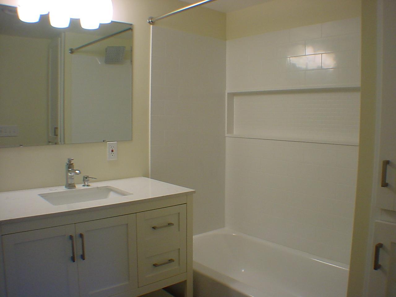 Lower vanity with room for guest towels, plenty of towel bars and hosting neutral decor.