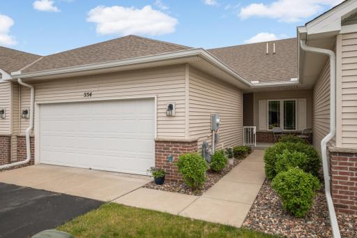 View of 2 car attached garage and walkway to covered patio and front entrance