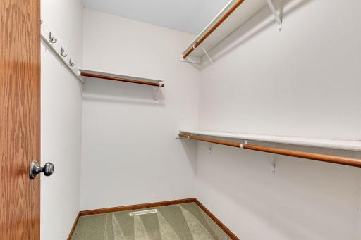 Primary walk in closet with built in shelving and hanger space.