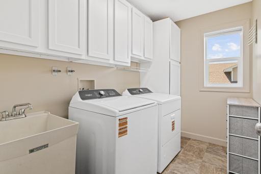 Upper level laundry features a laundry sink and built in cabinetry for added storage.