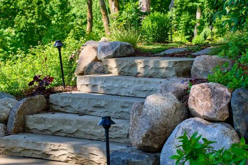 Solid rock steps and tiered retaining boulder walls are a beautiful addition leading around the home to the lake