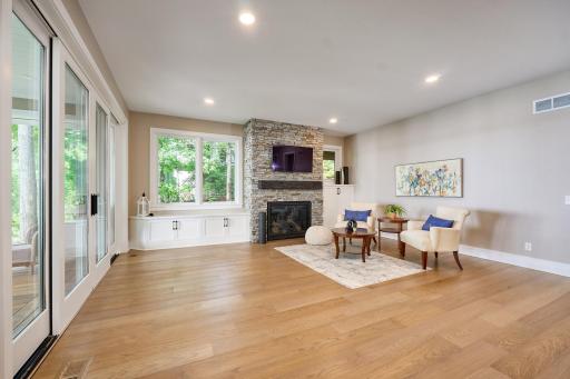 Premium White Oak Flooring, direct vent gas fireplace, custom cabinetry with a window-seat, recessed lighting, and large windows that flood this walkout-level family room with natural light
