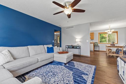 Natural daylight pours through expansive windows, illuminating the seamless flow from the kitchen into the dining area and onward to the living room. From the kitchen vantage point, the entire space feels connected and airy.
