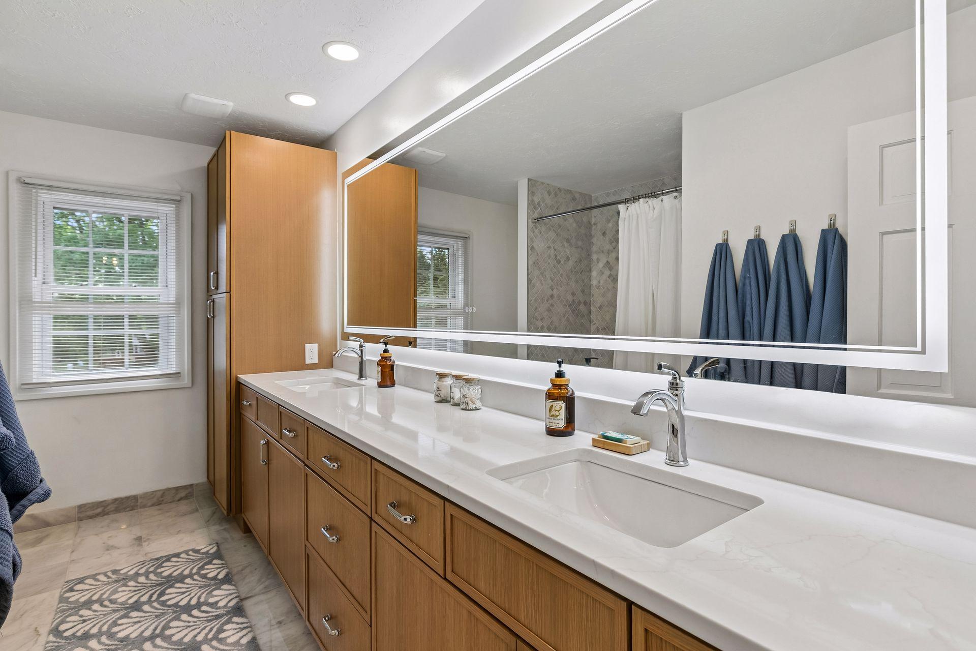 The recently updated second floor bath has a long quartz vanity top with dual sinks and a significant amount of storage. There is a tub/shower combination with tile surround and tile flooring.