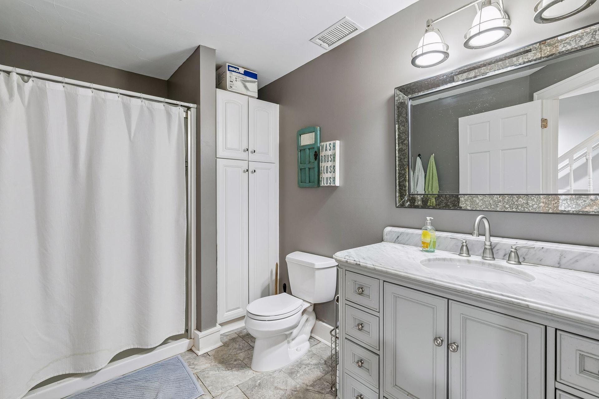 The lower level bathroom has an oversized shower, a linen cabinet and tile flooring.