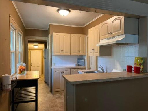 Kitchen with view of hallway to second bedroom and the door to the fenced in back yard.