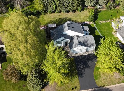 Yard is surrounded by trees with incredible rock wall flowering gardens