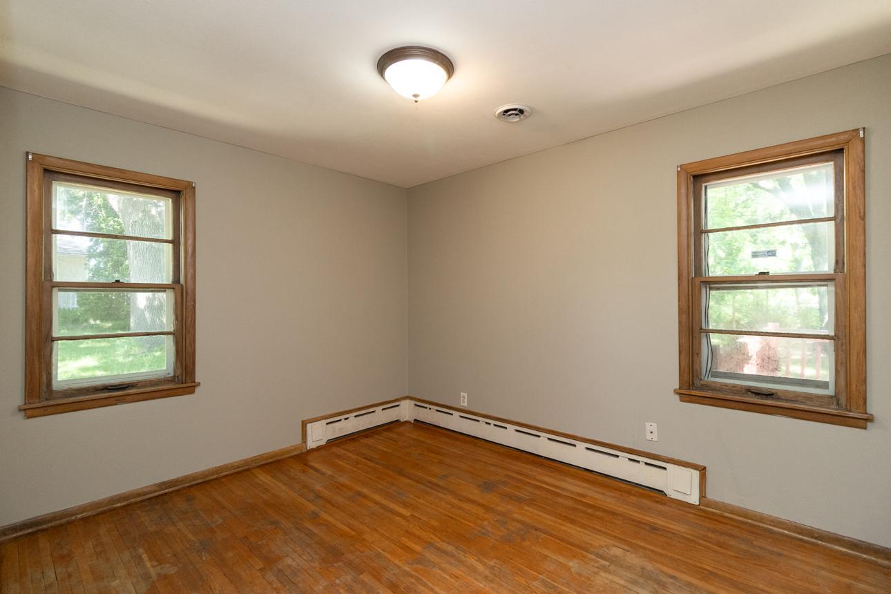 Main level 3rd bedroom with hardwood floors, closet space, and large windows for natural sunlight.