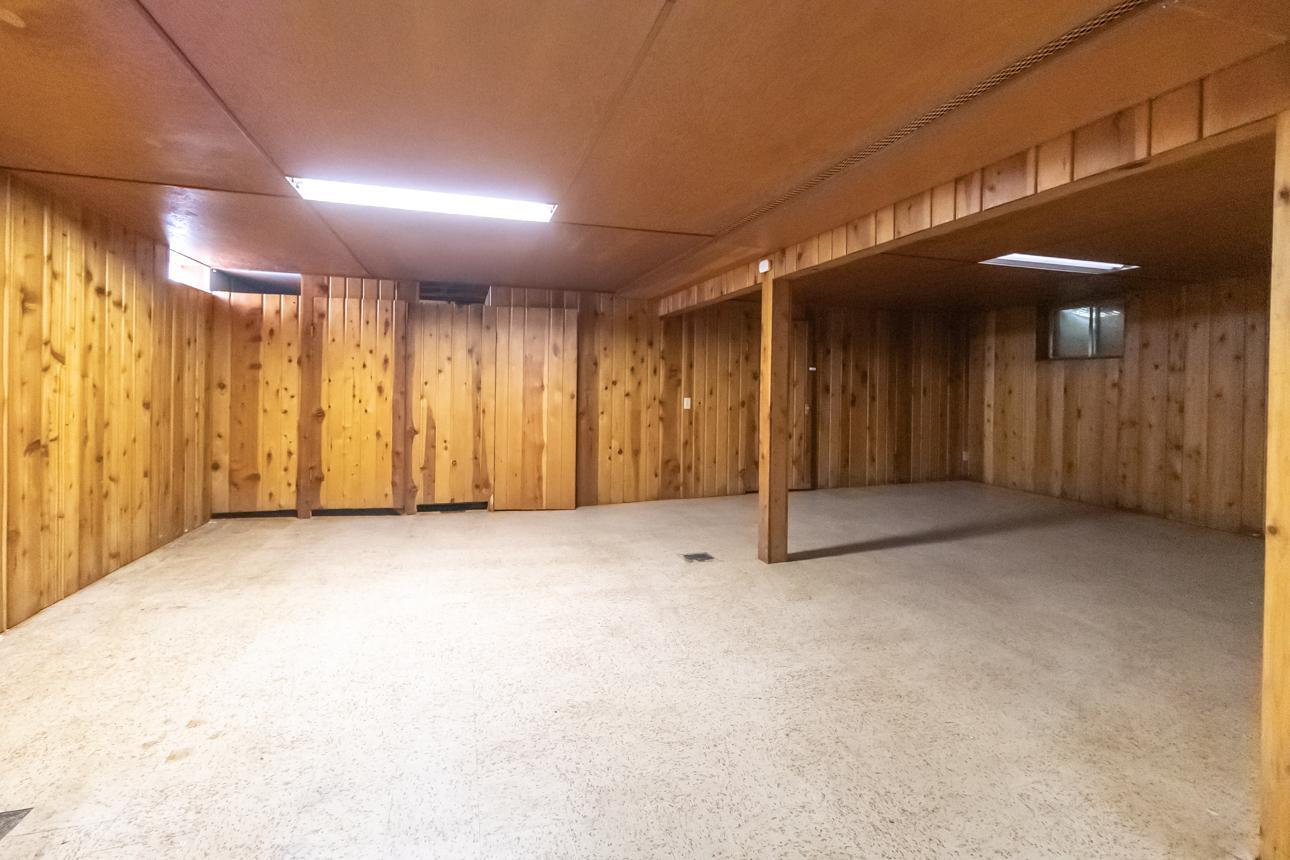 Spacious lower-level family room with wood-paneled walls and flexible layout for entertaining, hobbies, or additional living space.