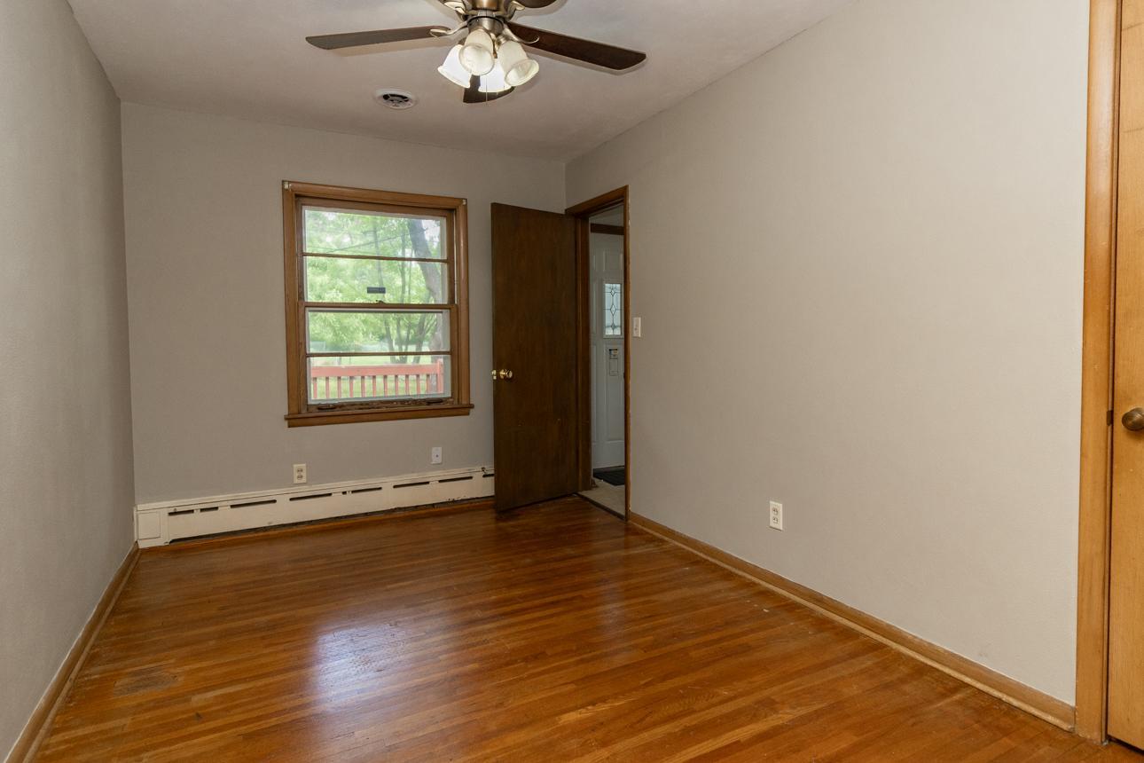 Main level 2nd bedroom with hardwood floors, ceiling fan and backyard views.