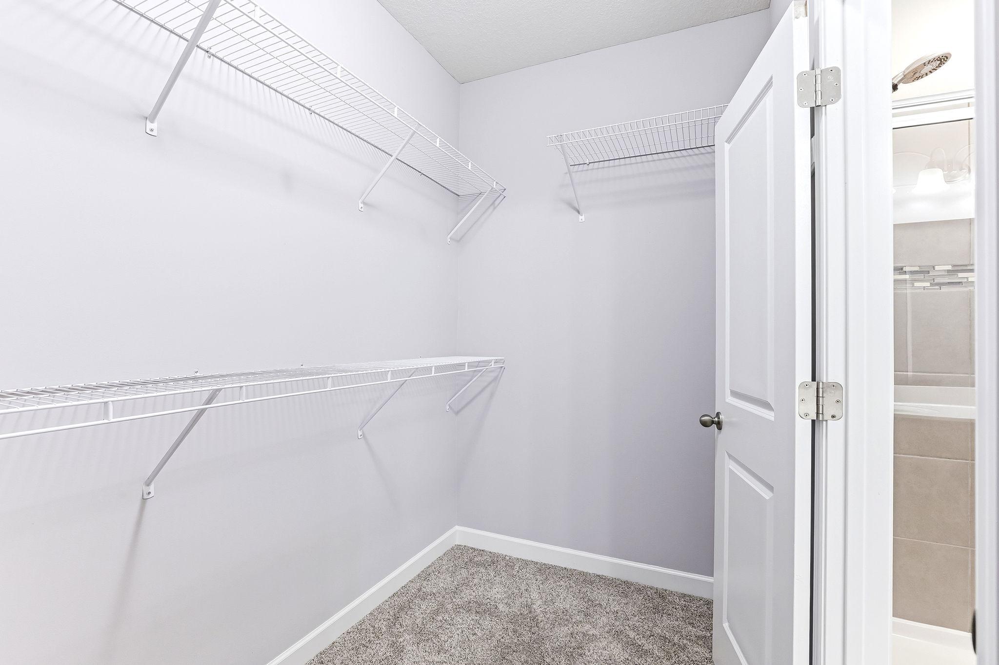 Well-organized walk-in closet offering generous hanging space, built-in shelving, and a clean, streamlined layout.