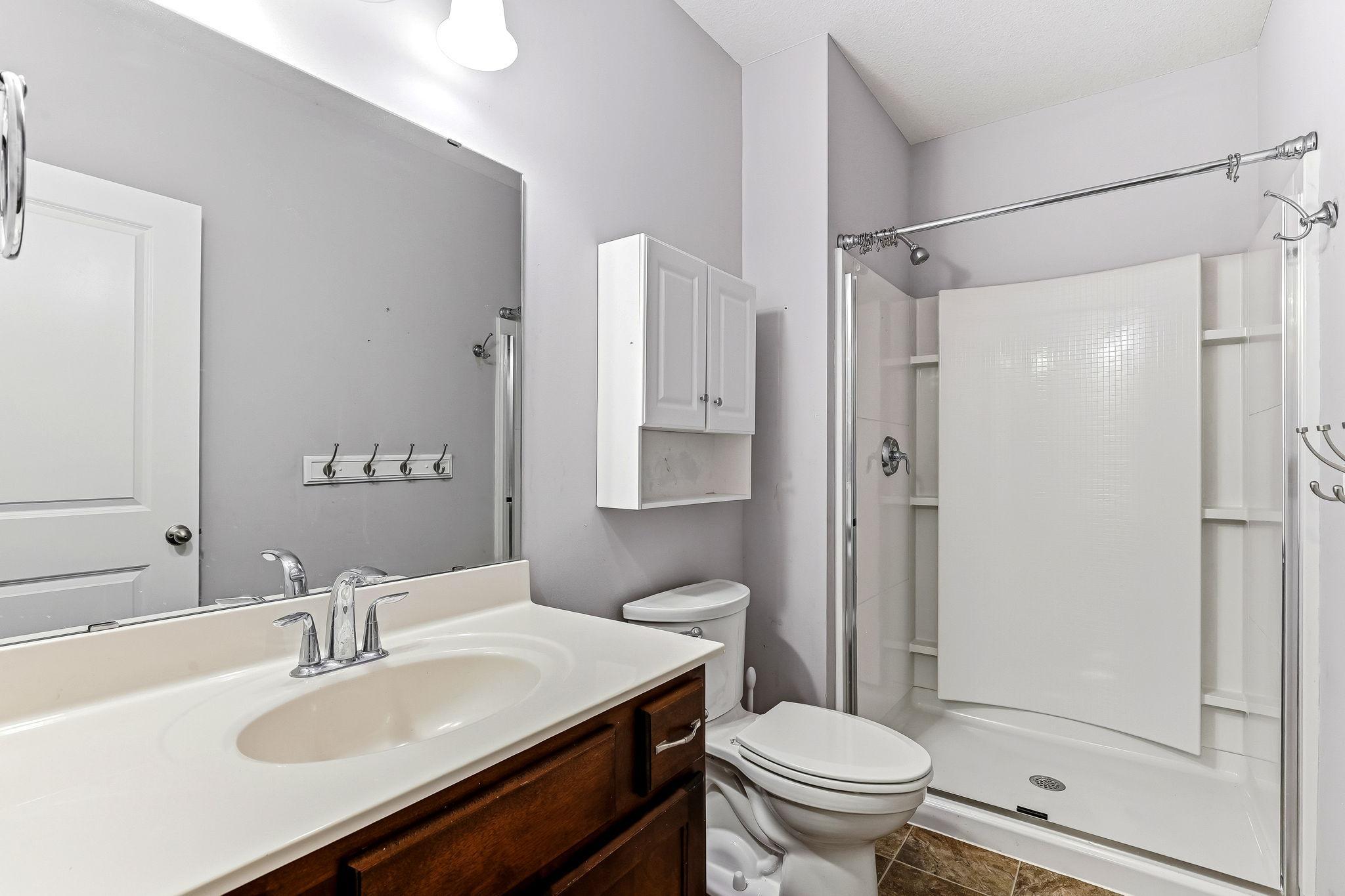 A clean and modern 3/4 bath on the lower level featuring a bright shower, fresh finishes, and convenient access from the family room and fourth bedroom.