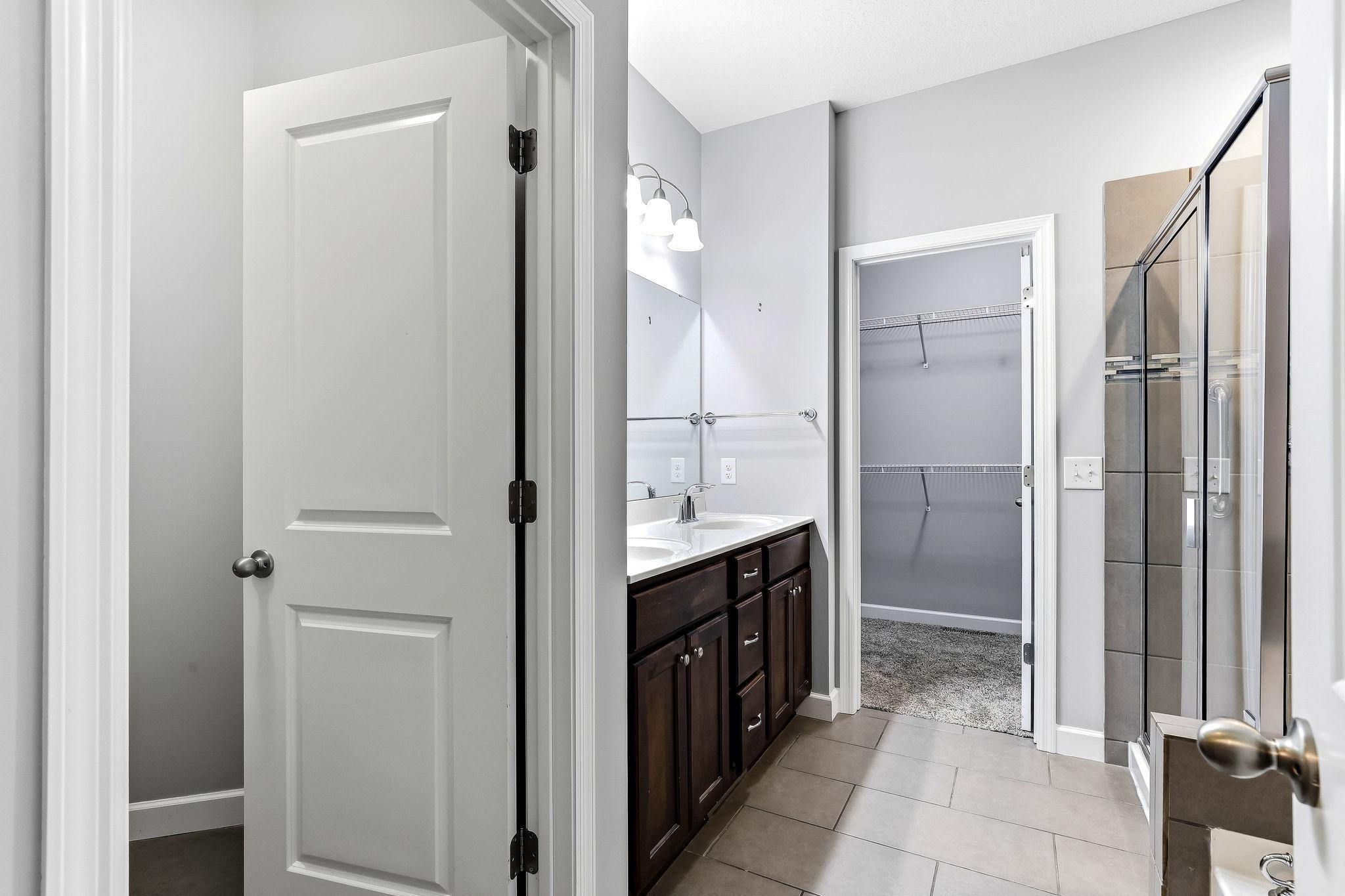 Beautiful primary bath featuring dual sinks, a separate soaking tub and walk-in shower, a private toilet closet, and direct access to the spacious walk-in closet.