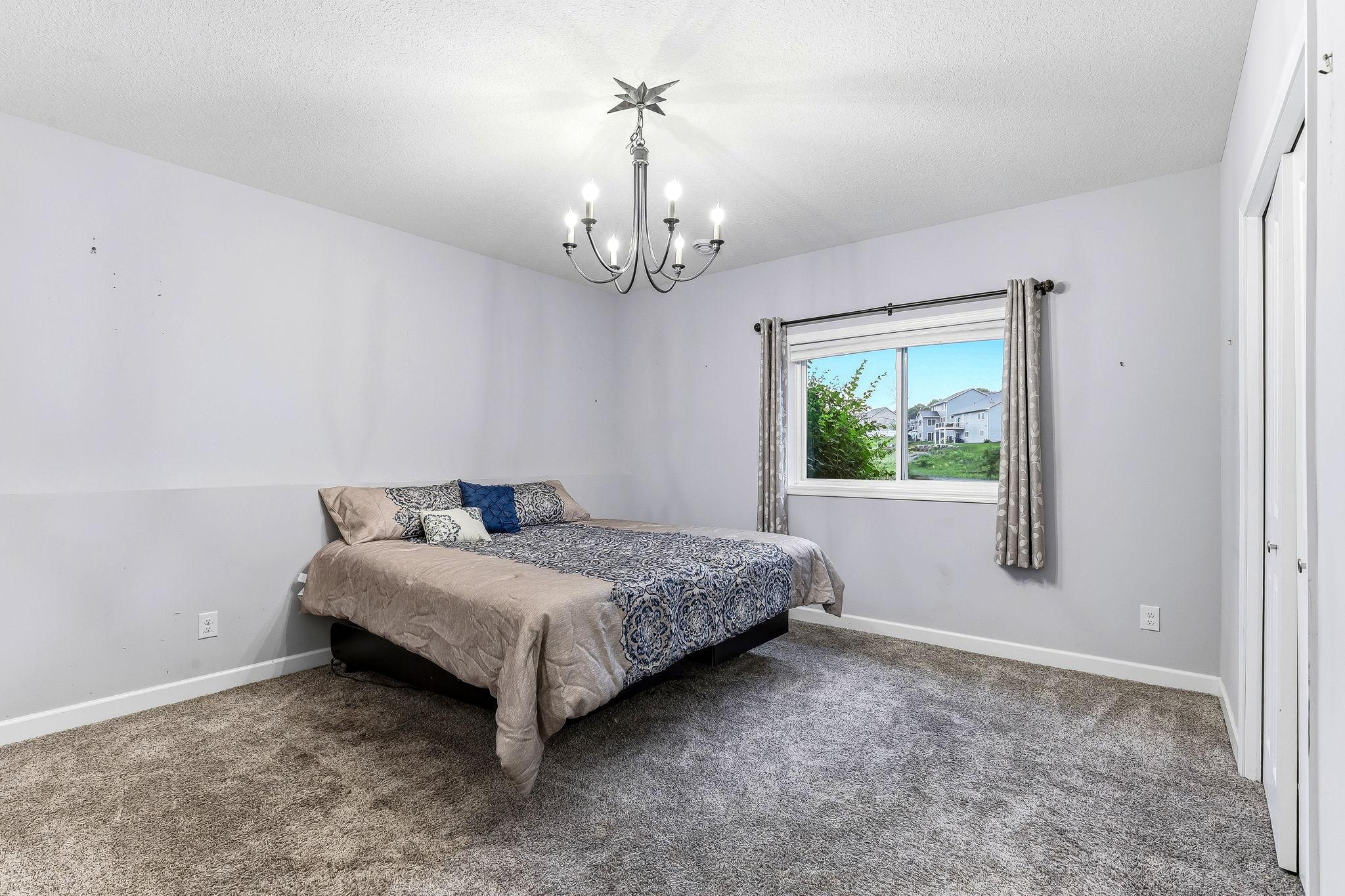 A private and comfortable fourth bedroom on the lower level, offering generous space, soft natural light, and a quiet setting ideal for guests, teens, or a dedicated work or hobby room.