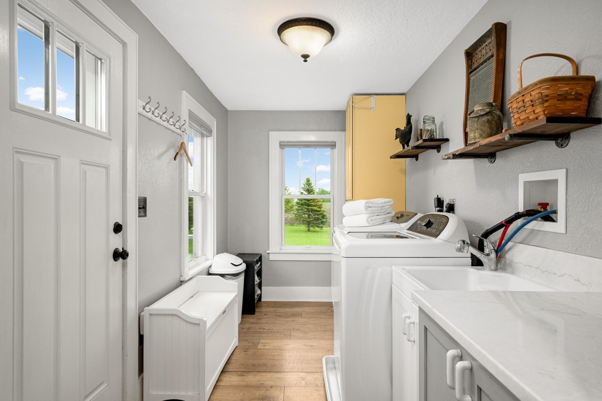 Main floor laundry room with utility sink and counterspace as well as storage.