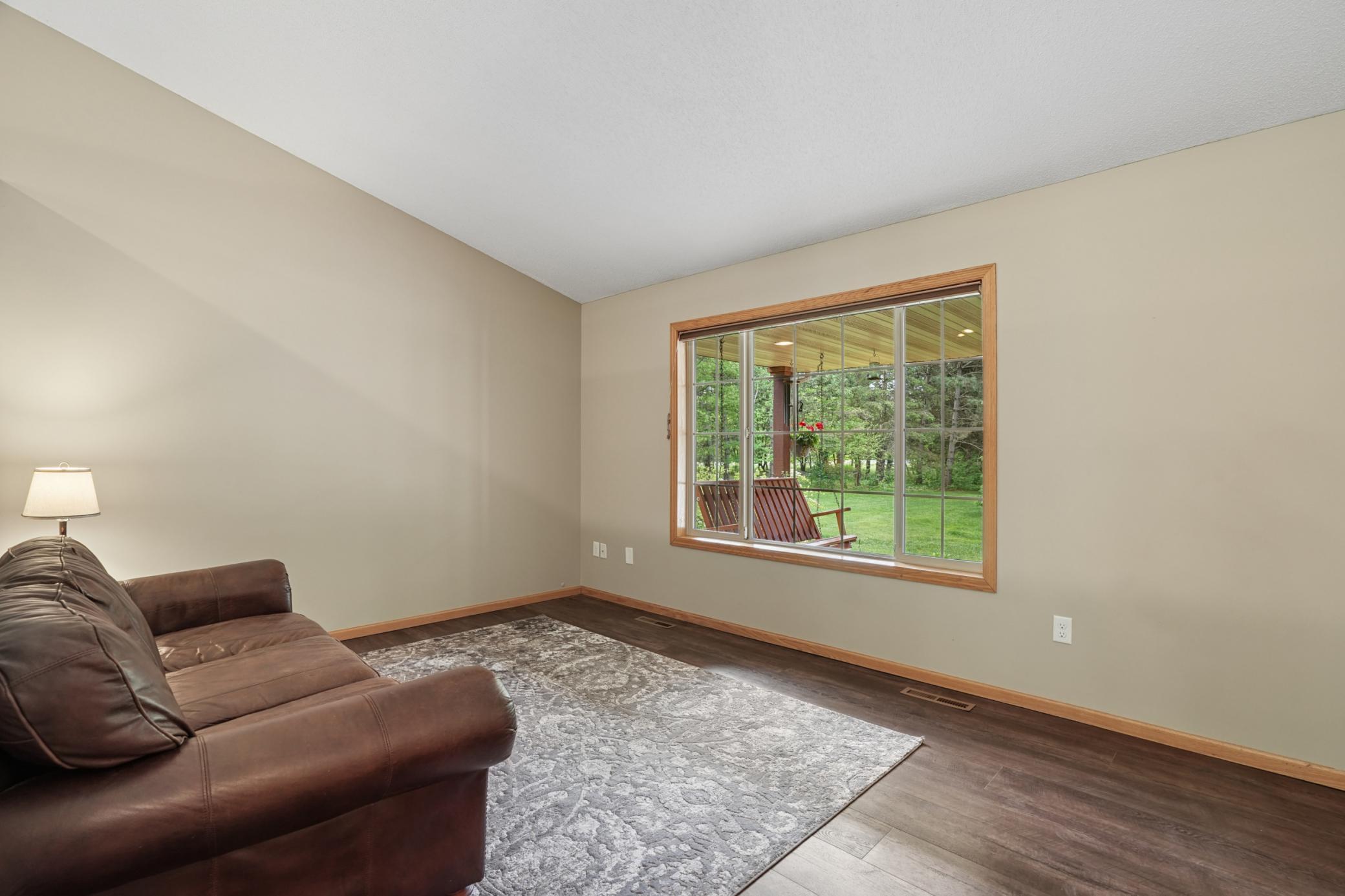Spacious front living room with neutral paint, vaulted ceilings, and a gorgeous view of the front yard with the large, picturesque window