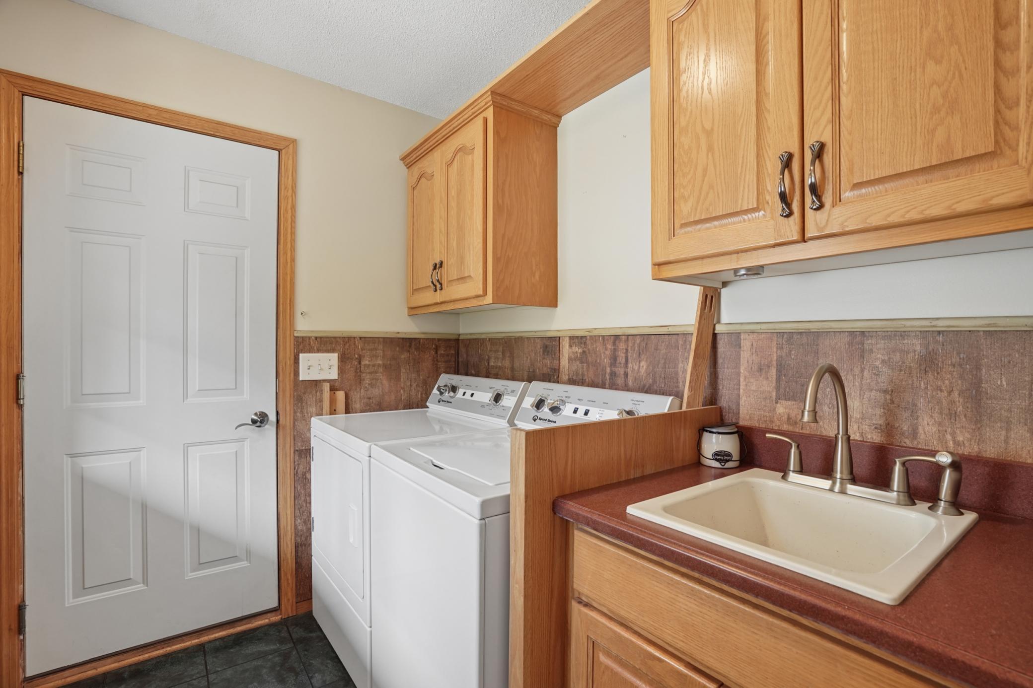 Main floor laundry offers convenience right off the garage! Upper solid oak cabinetry and a drop in laundry sink...