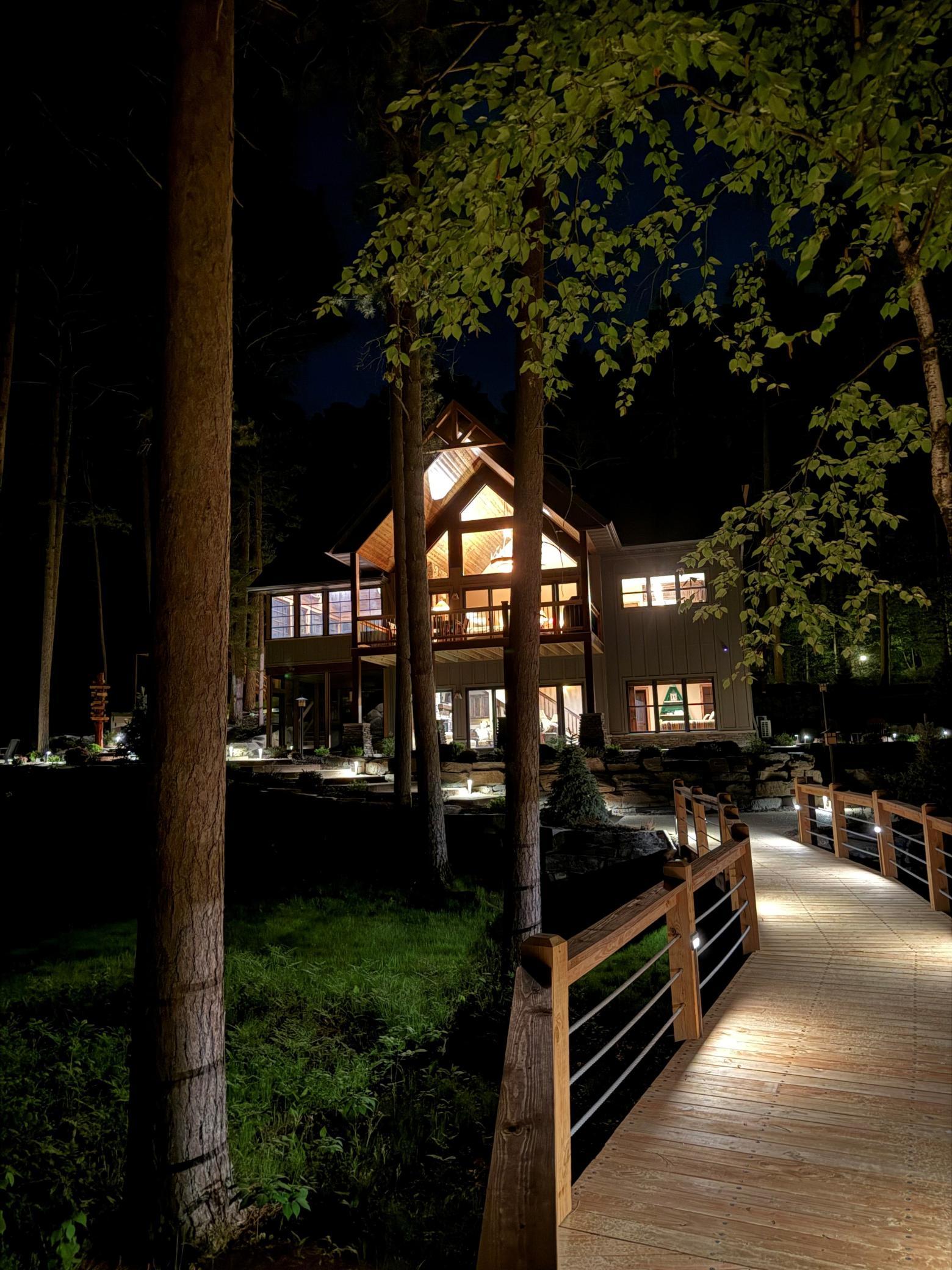 Welcome home day or night—beautifully illuminated walkway leads to a warm and inviting lakeside retreat.